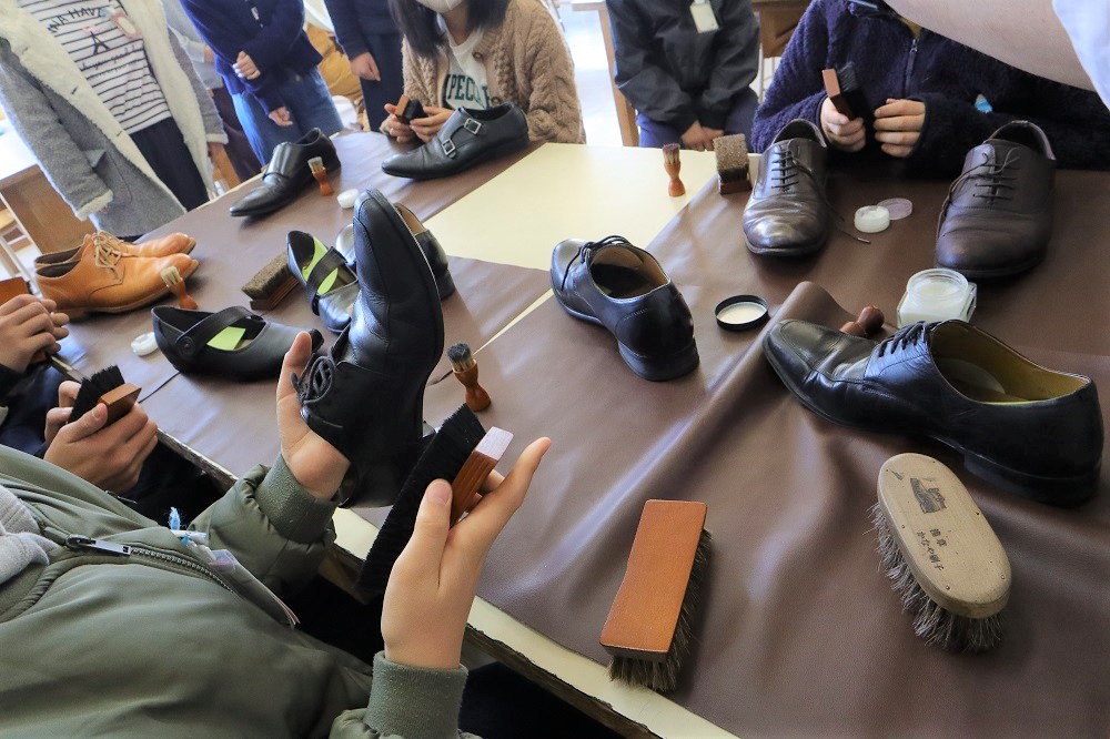 ブラシを手に持ち、靴磨きを体験する小学生